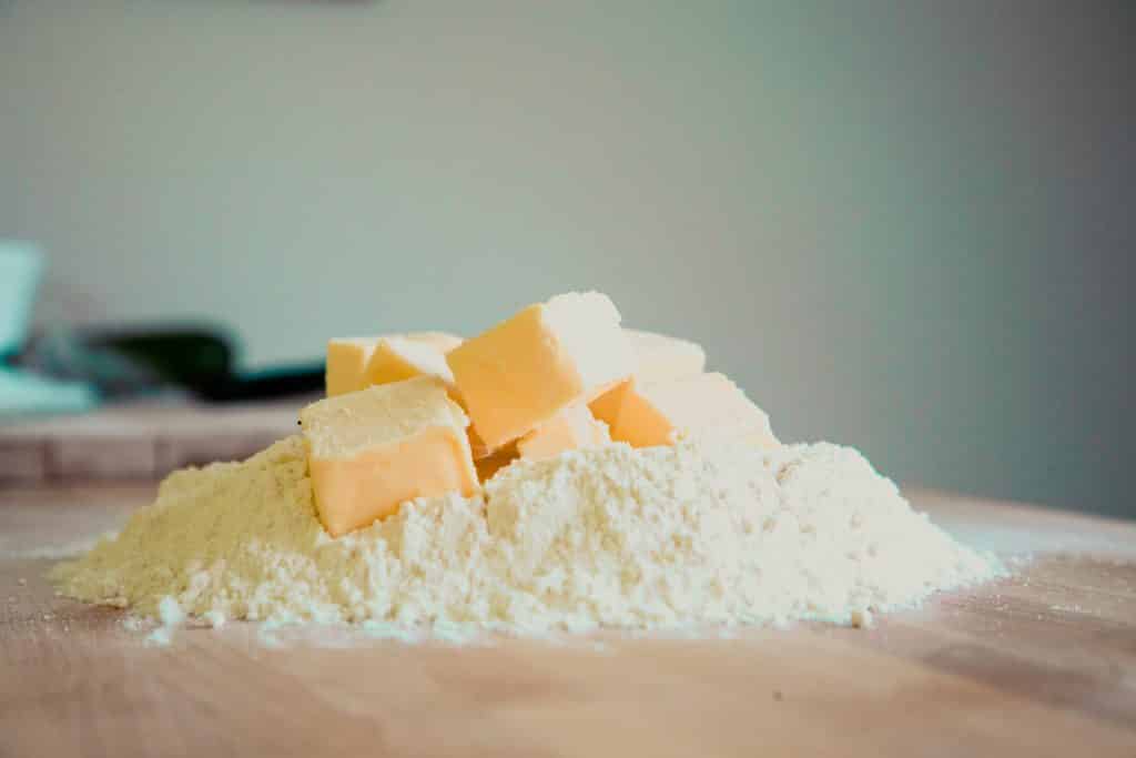 Pedaços de manteiga em cima de um montante de farinha de trigo