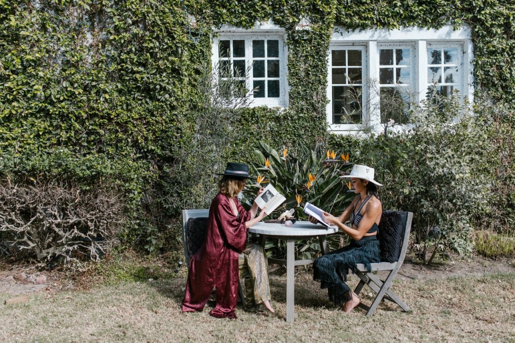 Mulheres sentadas em um jardim lendo.