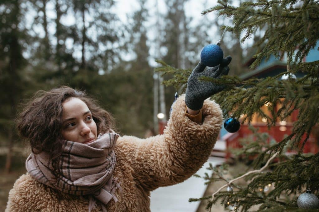 Menina tocando um enfeite de natal azul.