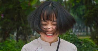 Mulher asiática sorrindo e com os cabelos balançando.