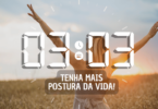 Hora igual 03:03 e texto "Tenha mais postura da vida!" aplicado por cima de foto de uma mulher loira de abraços abertos e jogados para cima. Ela está virada de frente para a natureza e sente o ambiente.