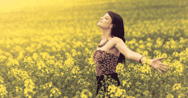 Mulher com os braços abertos em campo de flores