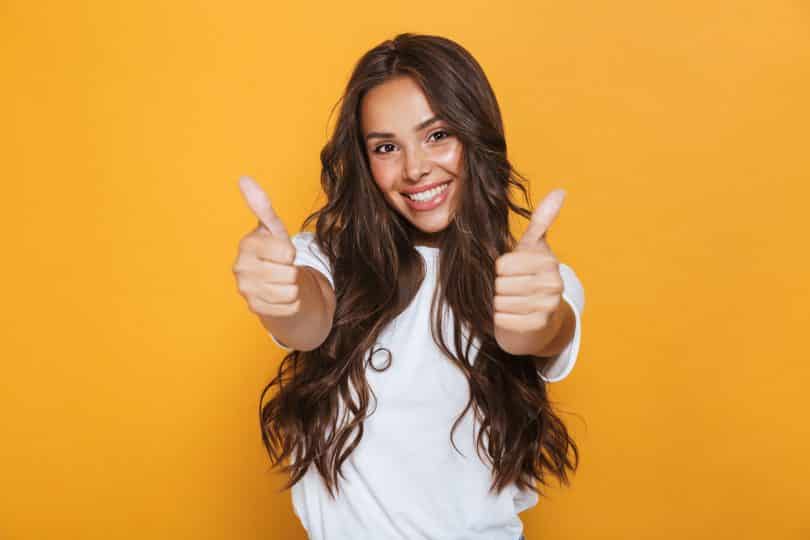 Mulher jovem feliz isolada sobre fundo amarelo, mostrando os polegares para cima gesto.