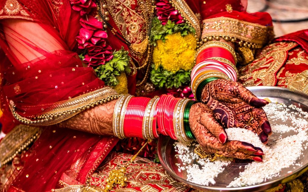 Noiva hindu indiana vestindo uma linda Lehenga vermelha em seu casamento e realizando o ritual tradicional de oferecer arroz a Deus com ambas as mãos