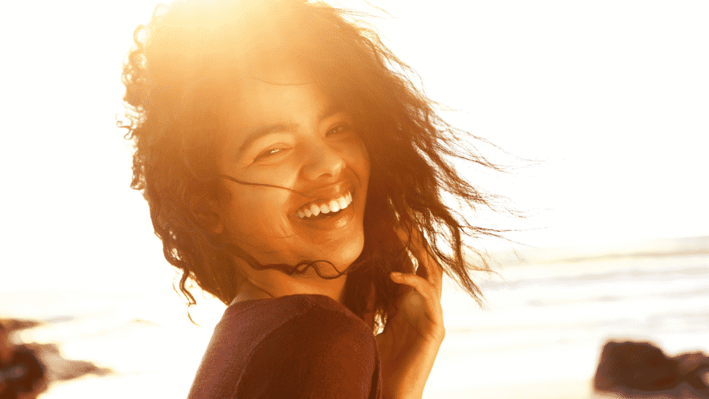 Mulher sorridente na praia durante o por do sol