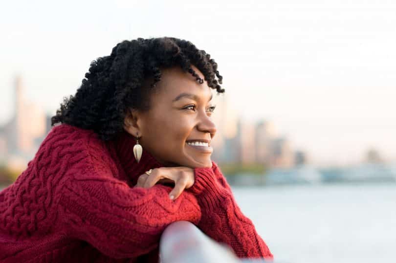 Mulher negra sorrindo olhando o horizonte.