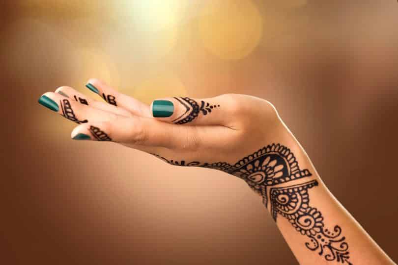 Mão de uma mulher com tatuagem mehndi.