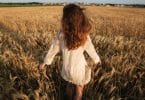 Mulher branca correndo num campo.