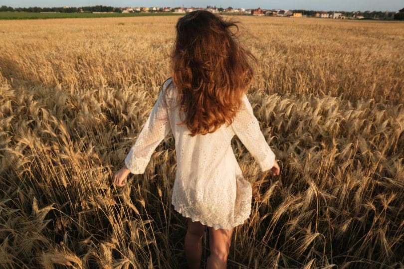 Mulher branca correndo num campo.