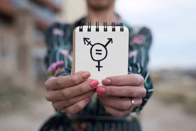 Mulher mostrando uma caderneta com símbolos que representam gêneros