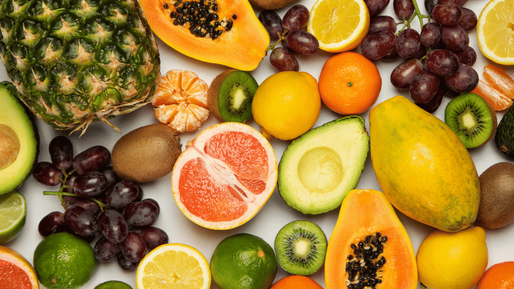 Diversas frutas inteiras e cortadas em cima de uma mesa branca