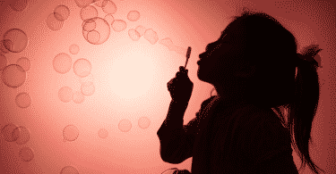 Silhueta de uma criança brincando com bolhas de sabão