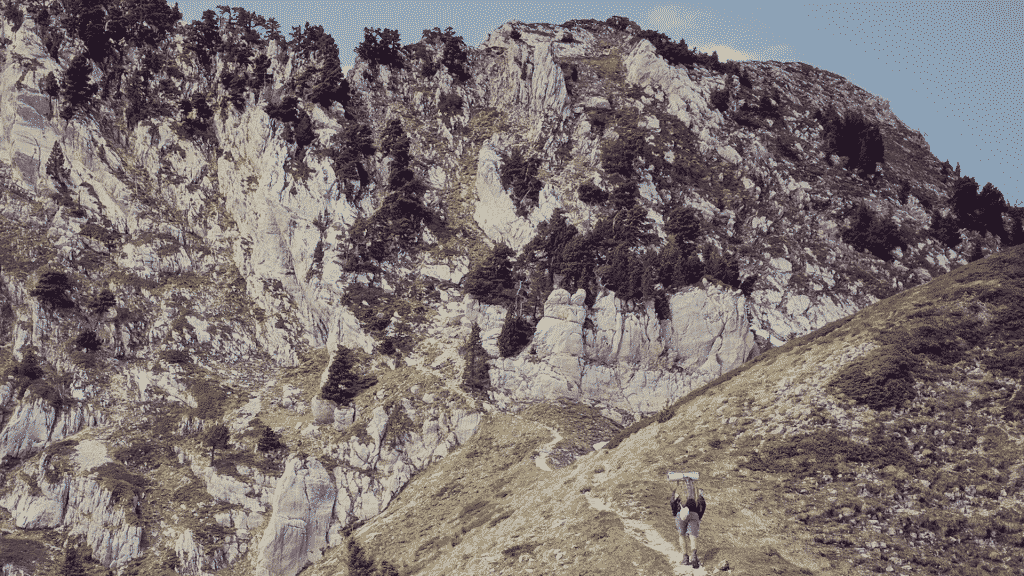 Uma pessoa fazendo uma escalada rumo à uma montanha.