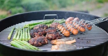 Linguiças e carne: um churrasco sendo feita numa churrasqueira.