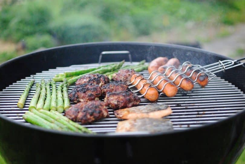 Linguiças e carne: um churrasco sendo feita numa churrasqueira.