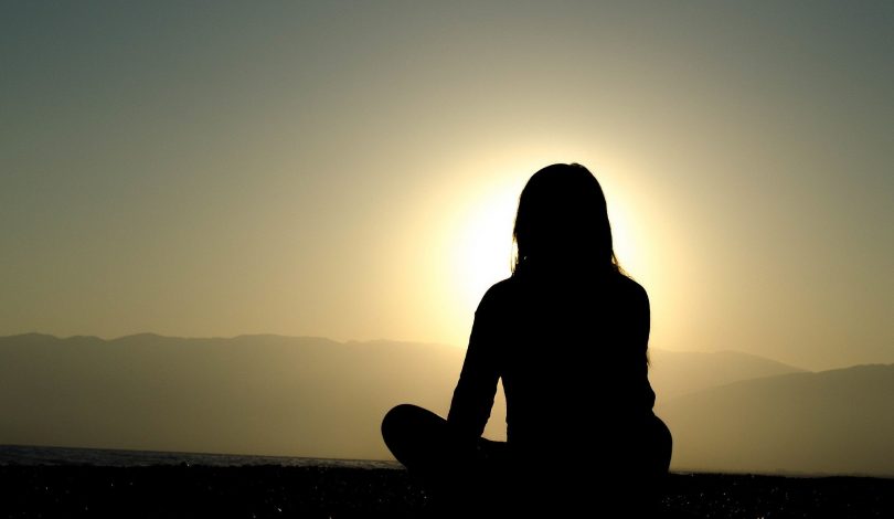 Sentada, uma silhueta feminina sombreada pelo sol.