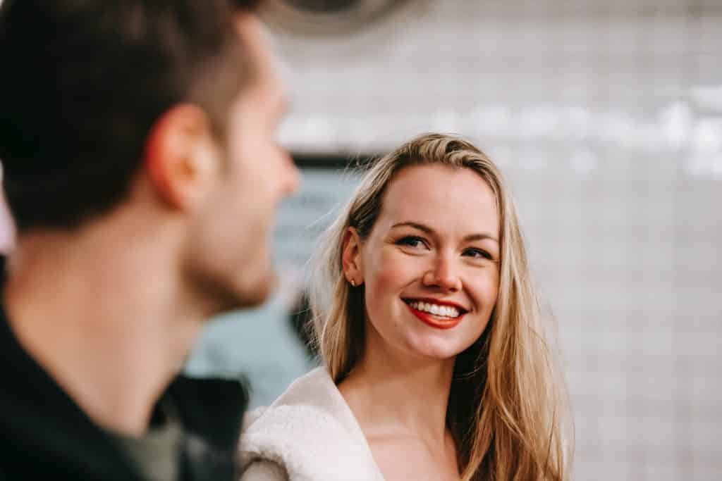 Uma mulher branca sorrindo e olhando para um homem branco.