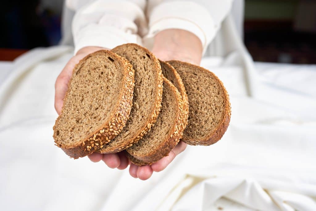 Duas mãos estendidas oferecendo pães.