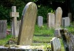 Várias lápides dispostas em um gramado de cemitério.