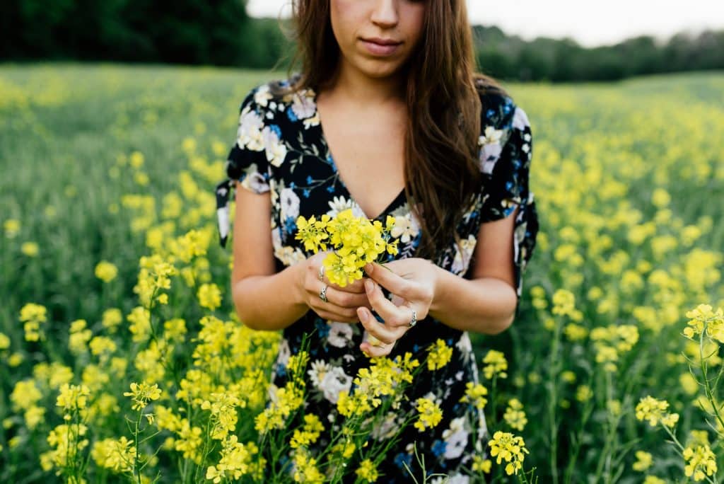 Mulher branca com flores amarelas.