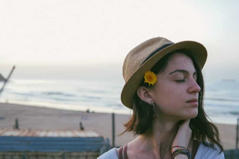 Mulher branca com flor no cabelo e olhos fechados.