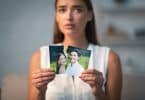 Uma mulher rasgando uma fotografia que tem um homem e uma mulher.