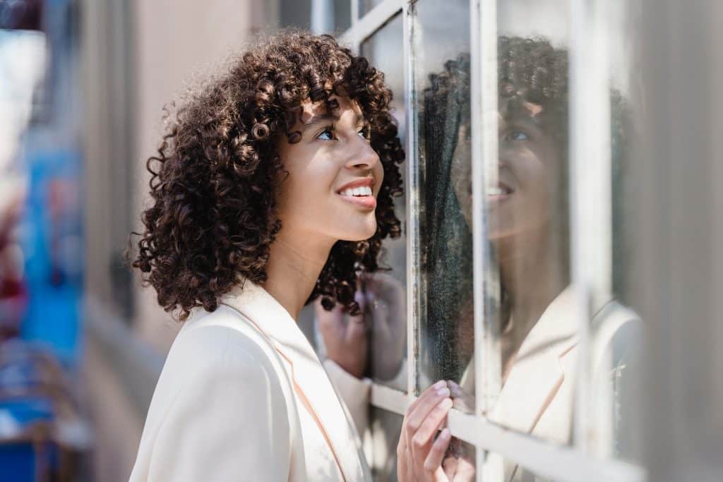 Mulher sorrindo olhando para uma janela