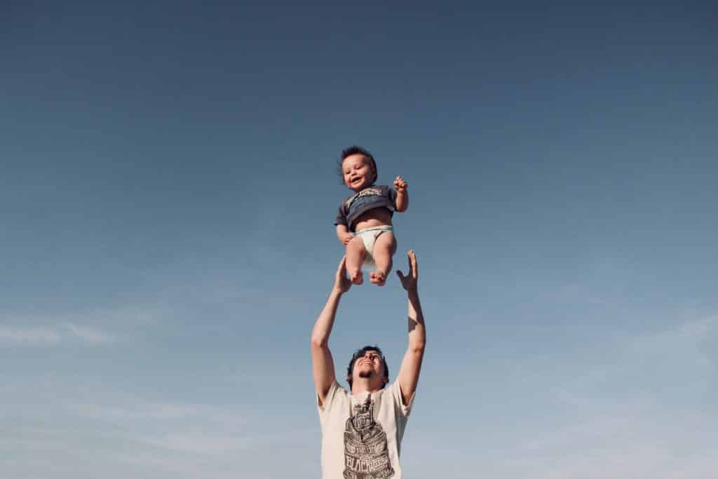 Pai jogando o seu bebê para o alto