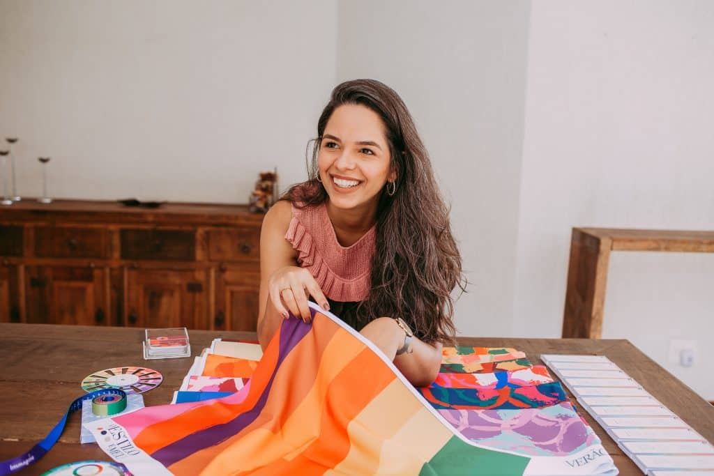 Mulher sorrindo enquanto segura uma bandeira colorida