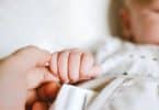 Bebê segurando o dedo de sua mãe