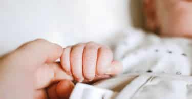 Bebê segurando o dedo de sua mãe