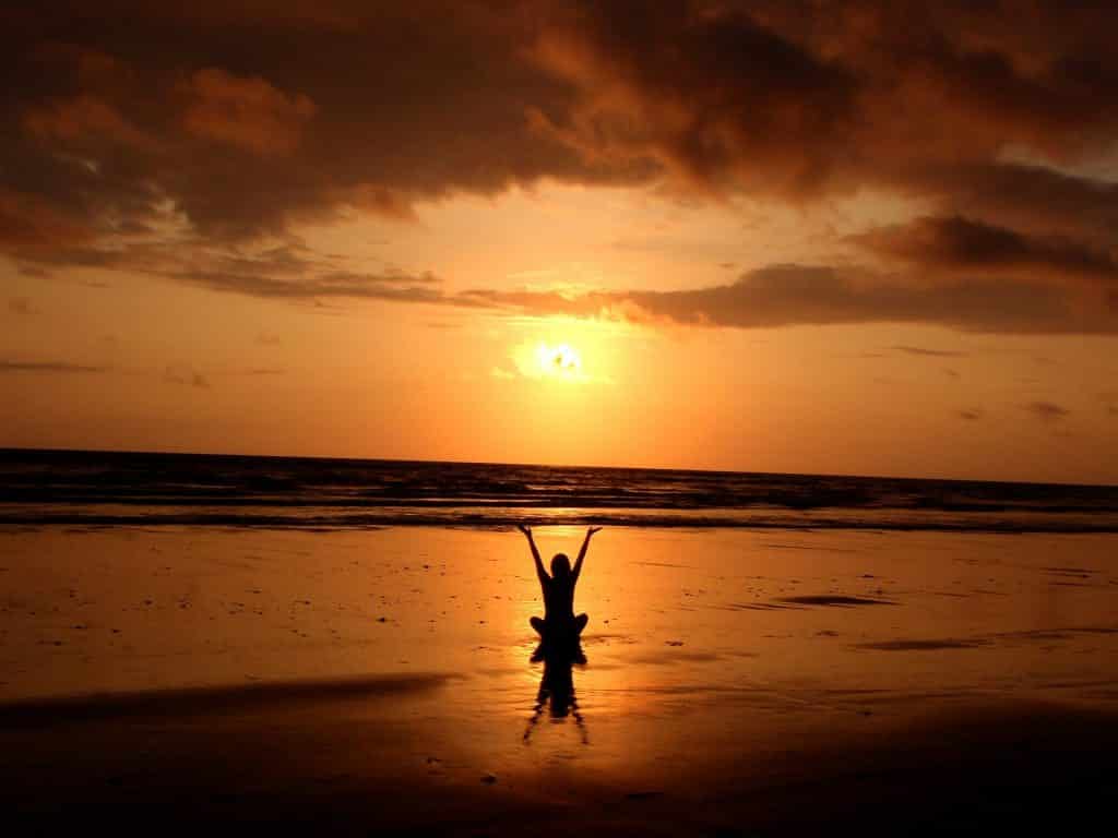 Mulher assistindo ao pôr do sol na praia