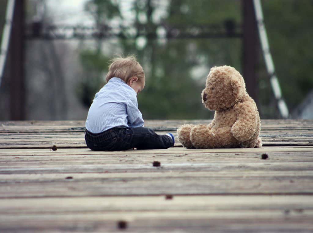 Bebê ao lado de um urso de pelúcia