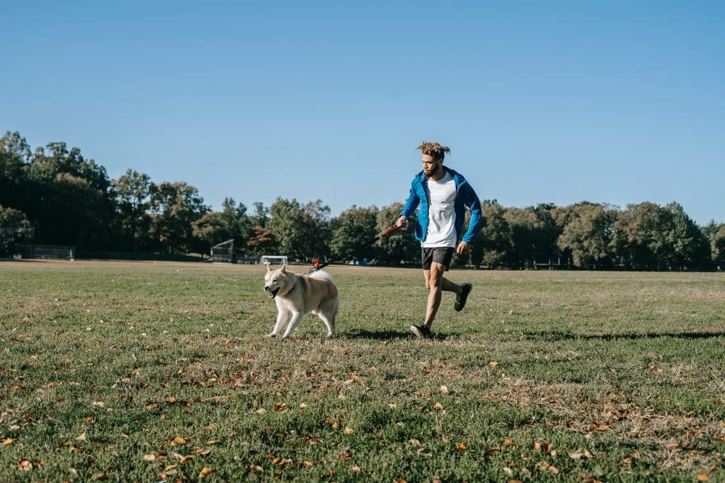 Homem correndo com seu cachorro em um campo