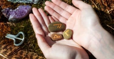 Mão segurando várias pedras com runas