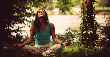 Mulher meditando sentada na grama