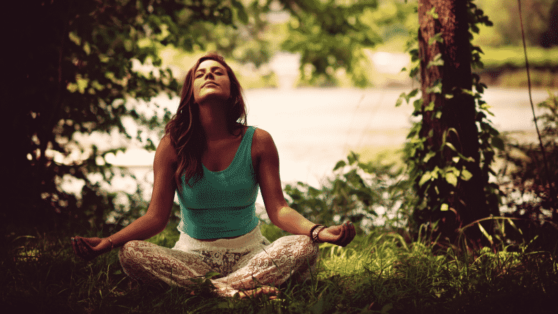 Mulher meditando sentada na grama