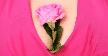 Flor rosa dentro do decote de uma blusa rosa
