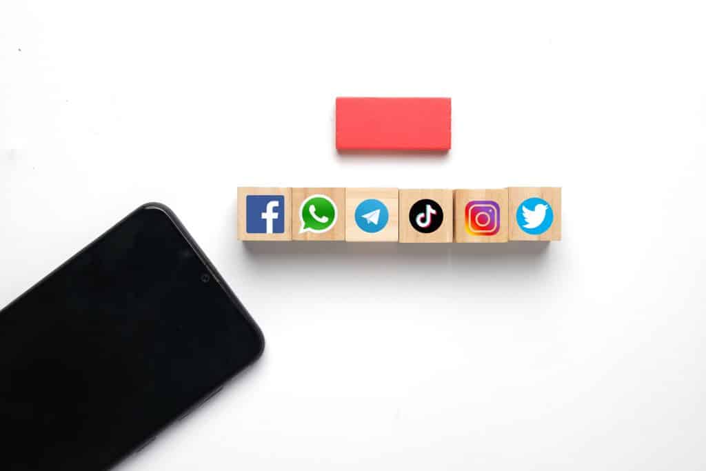 Smartphone com símbolo de mídia social em um bloco de madeira.