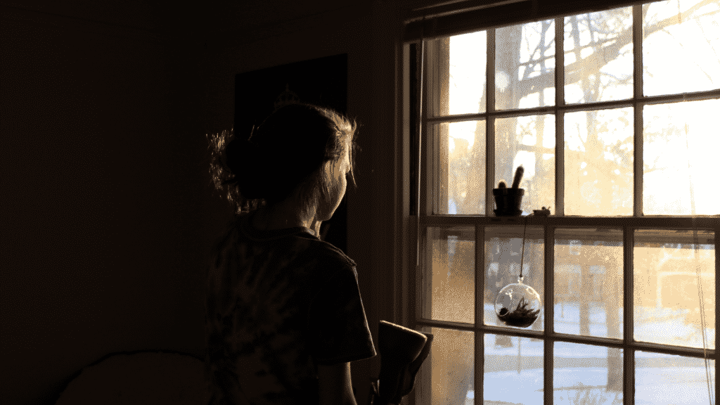 Silhueta de mulher olhando pela janela