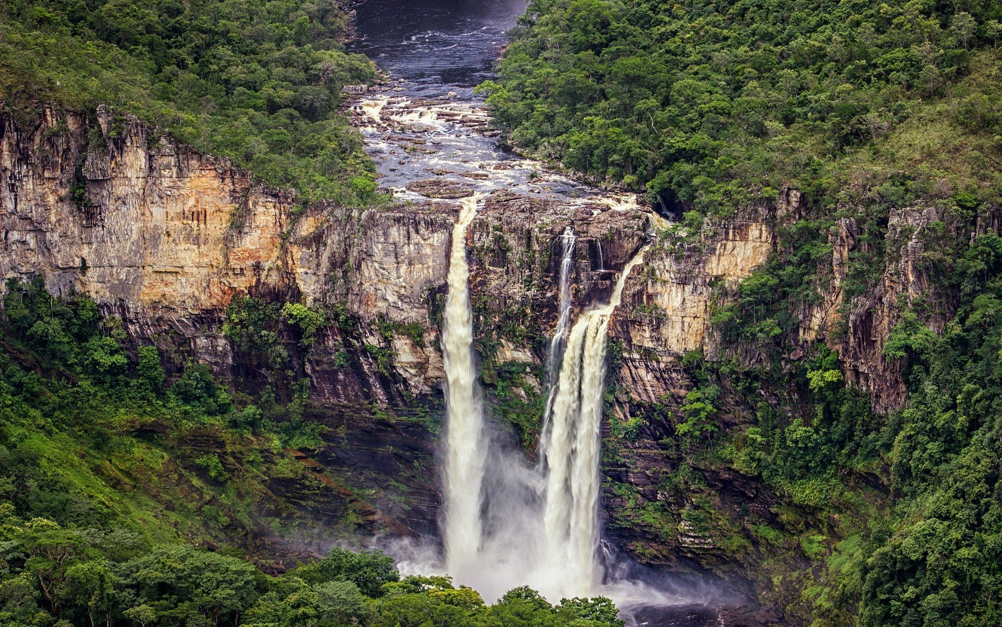 Cachoeira do Salto do Rio Preto vista de cima. Uma enorme cachoeira. Ao fundo, uma zona verde.