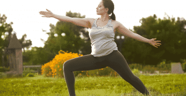 Mulher praticando posição de yoga em um campo aberto