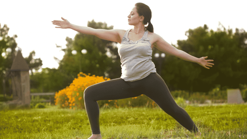 Mulher praticando posição de yoga em um campo aberto