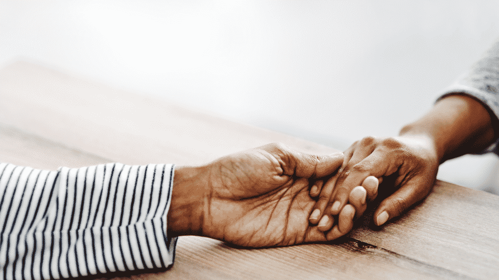 Imagem de uma mão de uma pessoa pegando a mão de outra pessoa