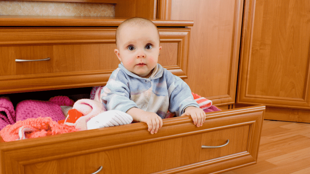 Bebê dentro de uma gaveta com roupas de lã