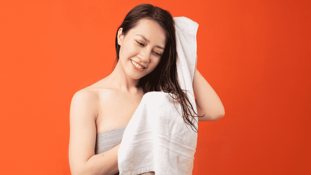 Mulher secando o cabelo com uma toalha branca