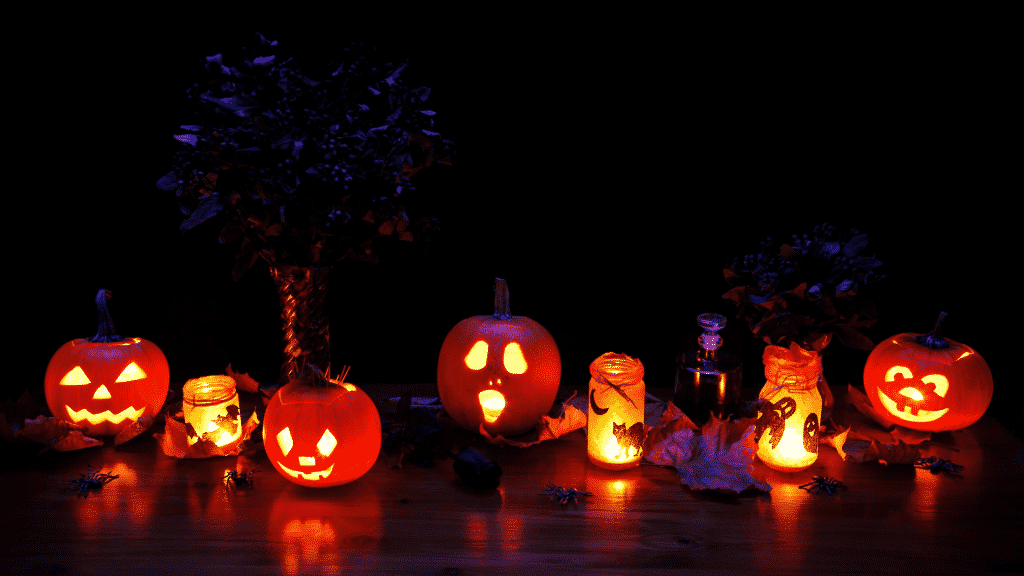 Diversos elementos de Halloween, como velas, abóboras e aranhas.