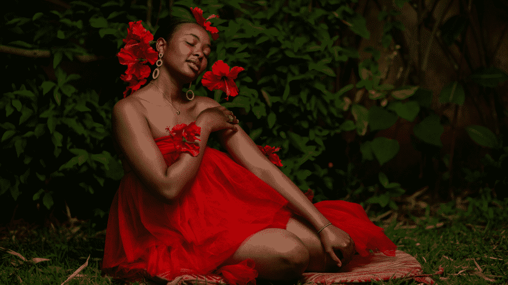 Mulher sentada em um jardim com um vestido e flores vermelhas