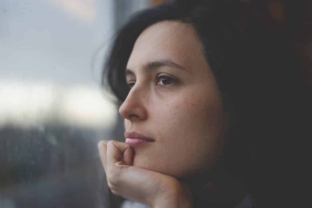 Uma mulher contemplando por uma janela.