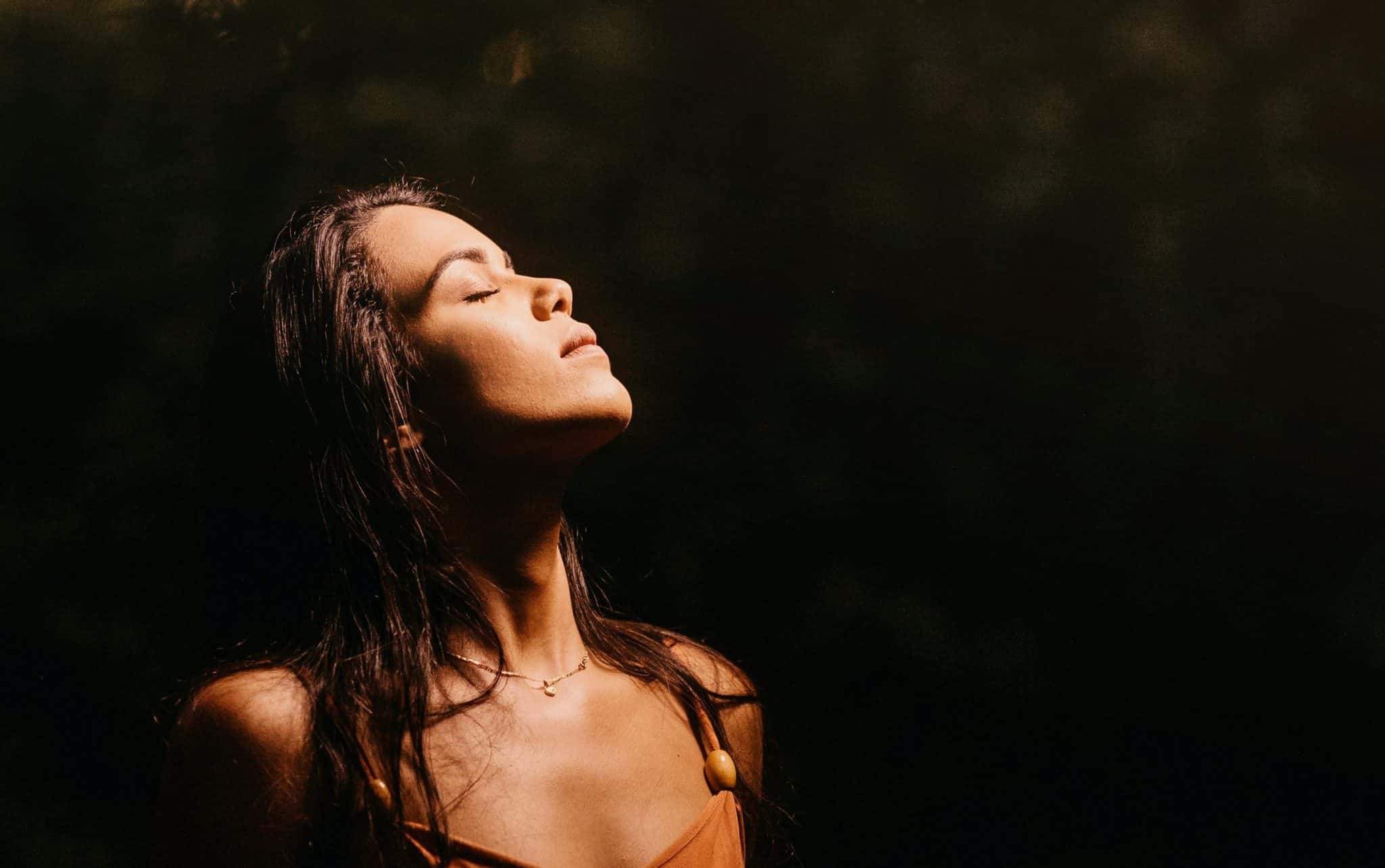 Uma mulher morena contemplando o alto.